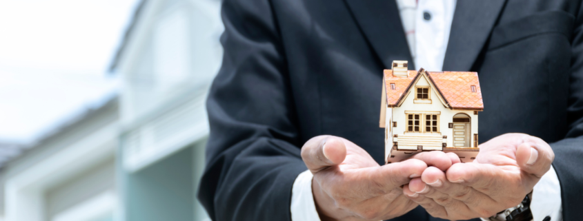 real estate agent holding a miniature of a house in his hands