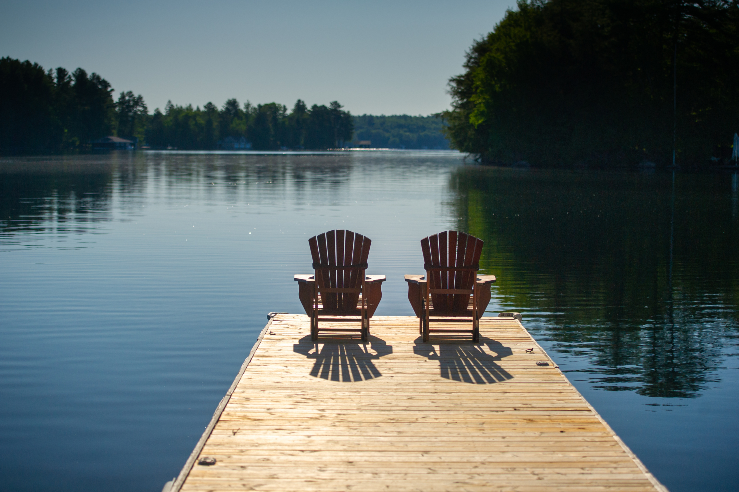 Adirondack chairs sitting on a wooden pier