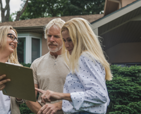 couple reviewing their life insurance with broker in front of home