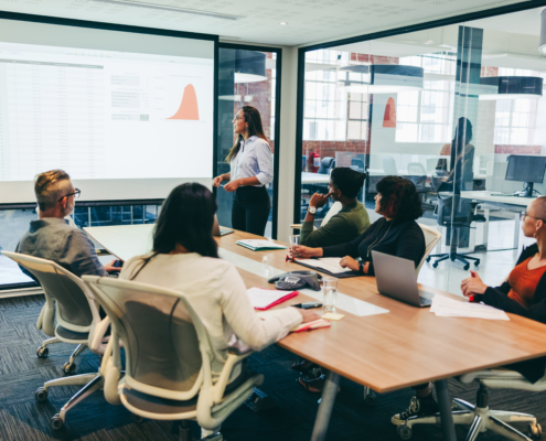 Team of creative businesspeople having a presentation in a boardroom. Group of modern businesspeople attending a financial briefing in a modern workplace. Businesspeople analysing statistical details.